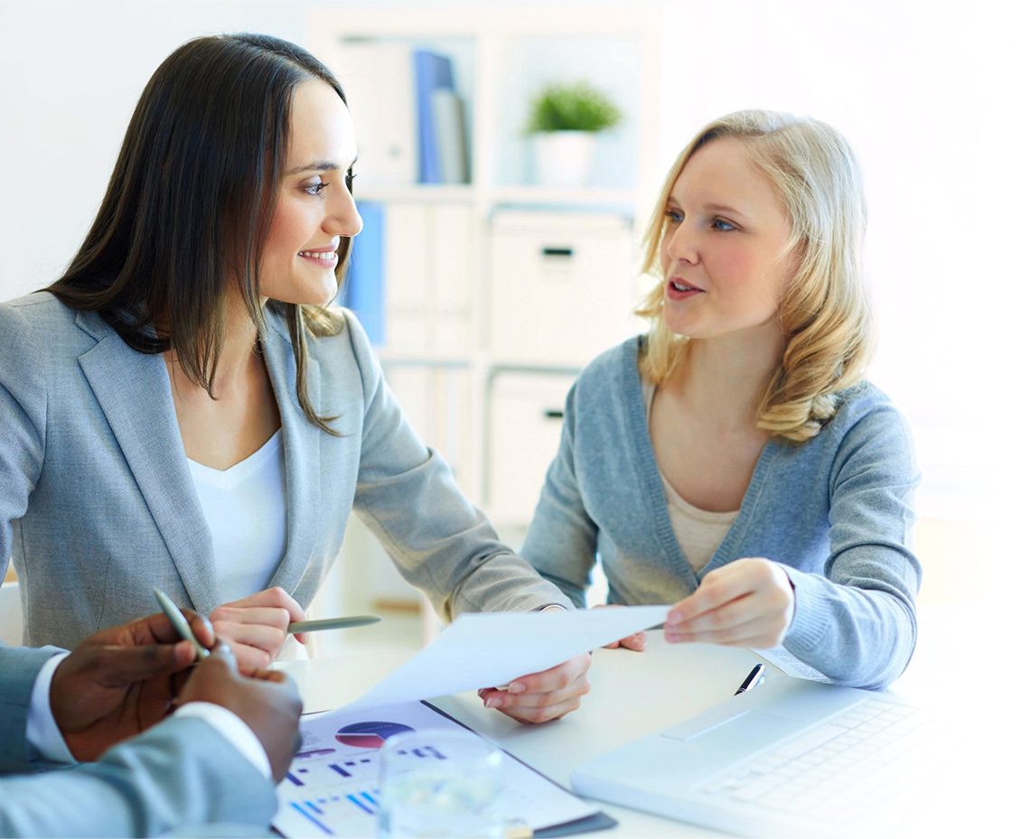 Two women sitting at a table talking to each other.