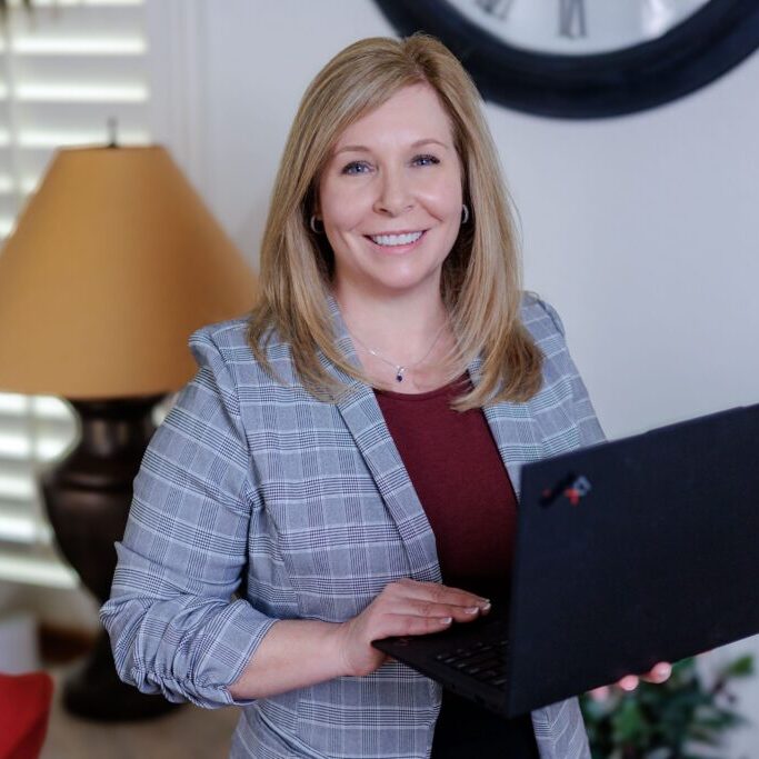 A woman holding a laptop in her hand.