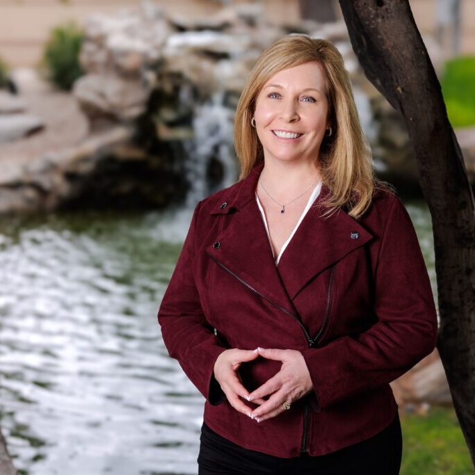 A woman standing in front of a waterfall.